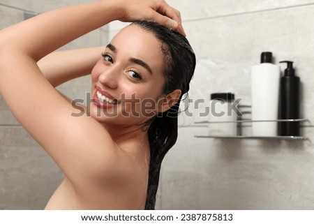 Beautiful happy woman washing hair in shower. Space for text