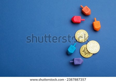 Dreidels with Jewish letters and coins on blue background, flat lay with space for text. Traditional Hanukkah game