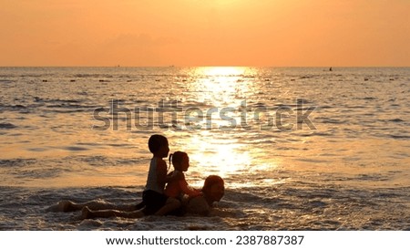 Silhouettes on colorful tropical ocean sunset background. Active parents and people outdoor activity on tropical summer vacations with children. Copy space.
