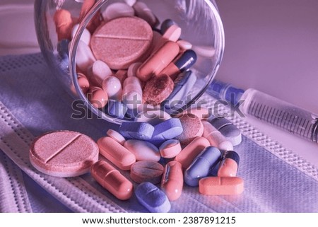 an overturned glass transparent glass on a medical disposable protective mask with colored pills , a photo in pink tones , the concept of medicine