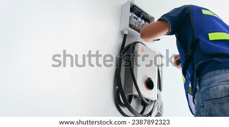Certified male Electrician Installing Home EV Charger Royalty-Free Stock Photo #2387892323