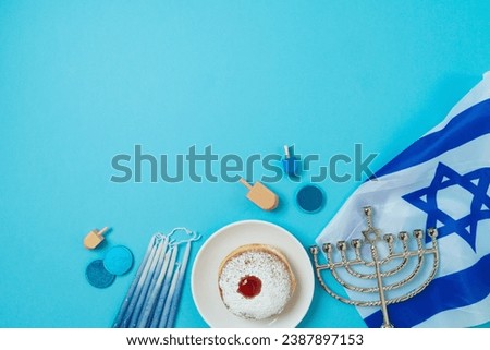 Jewish holiday Hanukkah concept with traditional donuts, menorah and Israel flag on blue background. Top view, flat lay Royalty-Free Stock Photo #2387897153