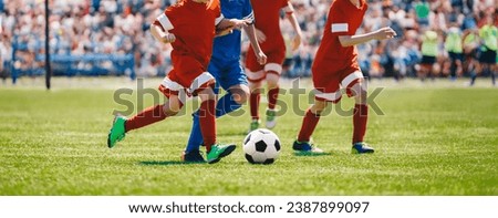 Football soccer match for children. Boys playing a football game in a school tournament. Picture of kids competition while playing a European football game at the stadium filled with spectators