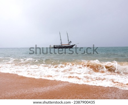Pirate ship on the high seas, horizontal landscape photo, Tour boat, Piracy on the beach. Brazilian Sea, Ilha Bela. Calm sea. Sand island, blue, sky. Royalty-Free Stock Photo #2387900435