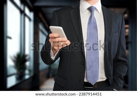 Smiling mature businessman posing in office with phone.