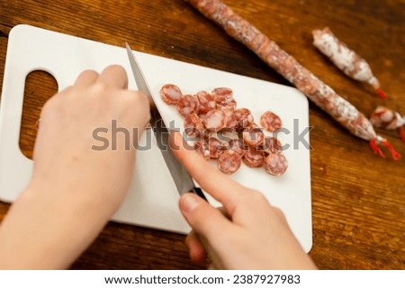 Culinary finesse: Female hands exhibit finesse while slicing sausage, showcasing the elegance of culinary technique and the refined artistry of food preparation Royalty-Free Stock Photo #2387927983