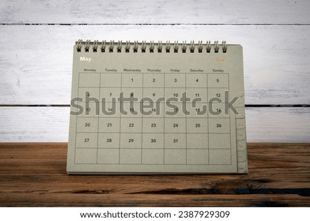 MAY 2024 cardboard desk calendar and planner on a wooden texture table.