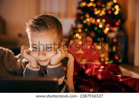 Portrait of a child watching videos on tablet at home on christmas and new year's eve.