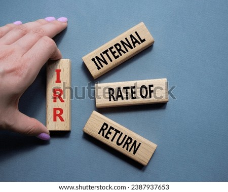 IRR - Internal Rate of Return symbol. Concept word IRR on wooden cubes. Businessman hand. Beautiful grey background. Business and IRR concept. Copy space.