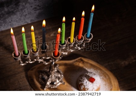 Jewish religious holiday Hanukkah with holiday Hanukkah (traditional candelabra), doughnut on a dark background