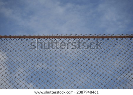 prison fence. painted Wire netting on a fence with blue sky behind close-up. Barbed mesh wire fence against blue cloudy sky. 