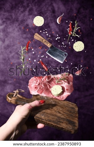Art photo levitation of a meat steak with ingredients for frying oil spices rosemary pepper garlic on a lilac background. High quality photo