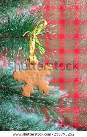 Snowflake shape gingerbread cookie on the Christmas Tree on red background with snow, selective focus and place for text