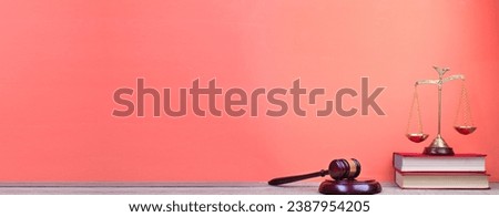 Law concept - Open law book, Judge's gavel, scales, Themis statue on table in a courtroom or law enforcement office. Wooden table, red background. Banner