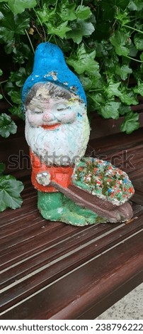 Dwarf decoration on the wooden bench in nature, white as snow, story, green, leaves