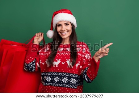 Photo of cheerful sweet lady santa helper dressed print xmas sweater holding shoppers empty space isolated green color background
