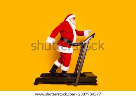 Full body profile photo of eccentric aged santa running treadmill race track weight loss new year time isolated on yellow color background Royalty-Free Stock Photo #2387980577