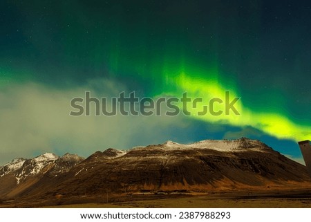 In Iceland, aurora borealis brightens dark skyline around sunset with magnificent colors of green and purple, forming unique icelandic surroundings. Around northern lights, stars sparkle.