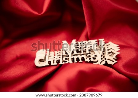 wooden letters saying Merry Christmas on red shiny satin fabric