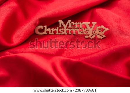 wooden letters saying Merry Christmas on red shiny satin fabric