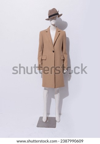 Female mannequin in fashion brown coat with hat clothes on white background 