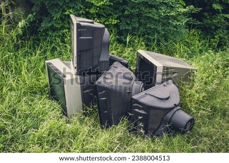Broken television stacked for disposal outdoor. Electronic recycling waste of discarded televisions. Royalty-Free Stock Photo #2388004513