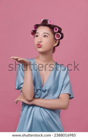 Beautiful woman with hair-curlers doing funny faces Royalty-Free Stock Photo #2388016985
