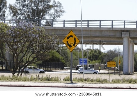 Roundabout traffic signs on a highway with cars passing by