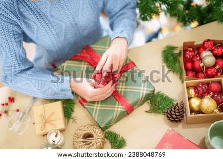 Woman in knitted sweater wrapping christmas presents with eco paper girl packing christmas gifts Xmas holiday concept.