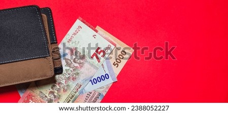 A wallet and new rupiah banknotes issued in 2022 isolated on red background