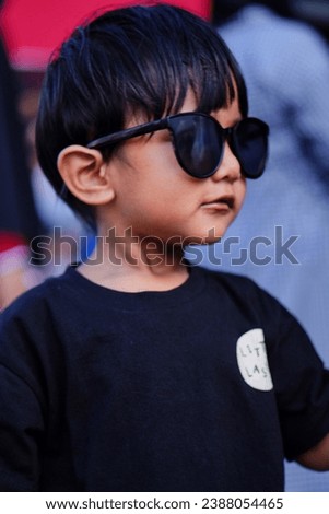 Close up A black-haired boy wearing sunglasses and a black shirt in portrait mode. Handsome boy model. Royalty-Free Stock Photo #2388054465