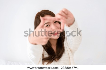 Young asian woman happy and making frame with fingers on white background in house Royalty-Free Stock Photo #2388066791