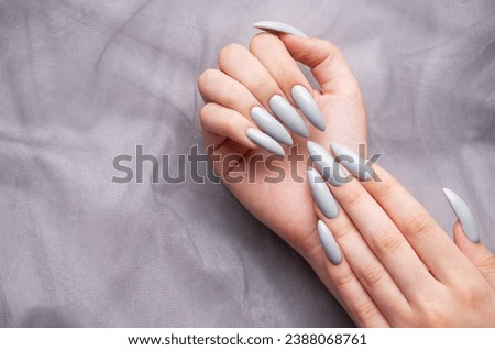 Beautiful painted in grey nails on grey lace background.