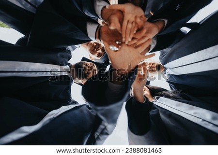 Young graduates in caps and gowns celebrate their achievements in a park. Students, faculty, and friends stand in a joyful circle, creating inspiring university memories. Royalty-Free Stock Photo #2388081463