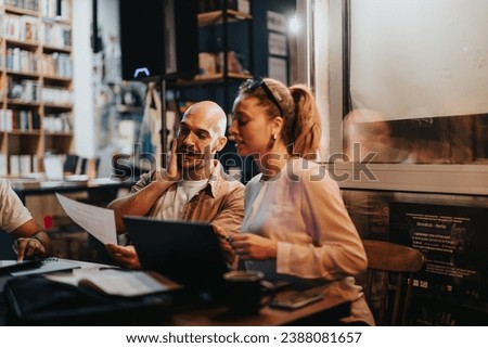Business partners meet in a coffee bar, discussing project details, budget, and profitability. Their confident teamwork and remote work abilities ensure success. Royalty-Free Stock Photo #2388081657