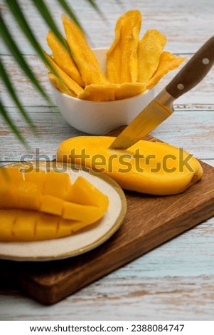 Vertical photo of a plate with sliced juicy pulp of tropical sweet mango. Healthy fruit ripe snack of ripe mango and slices of sweet candied fruits. 