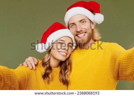 Close up merry young couple two friends man woman wears sweater Santa hat posing do selfie shot pov on mobile cell phone isolated on plain green background. Happy New Year Christmas holiday concept