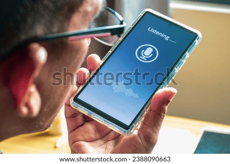 Close-up of a South Asian man talking to a voice translator mobile application. Selective focus.