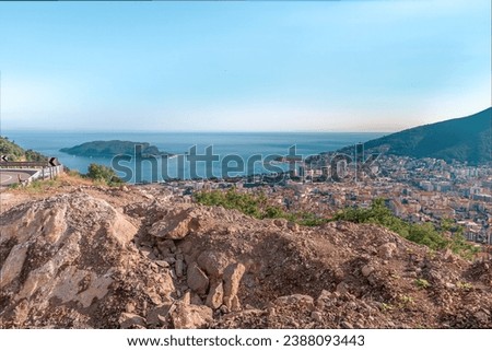 View from the top of the mountains to the ocean horizon. Drone view of the city of Budva among the hills and the Sveti Nikola Island in the blue waters of the Adriatic Sea in Montenegro Royalty-Free Stock Photo #2388093443