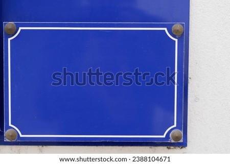 blue Paris street plate sign empty of text hanging on the wall in the Parisian street