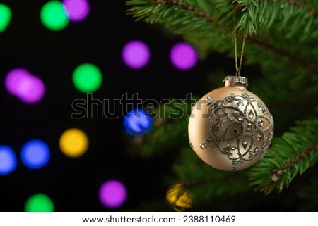 Christmas composition. Beautiful golden ball on a Christmas tree closeup on a sparkling dark background.
