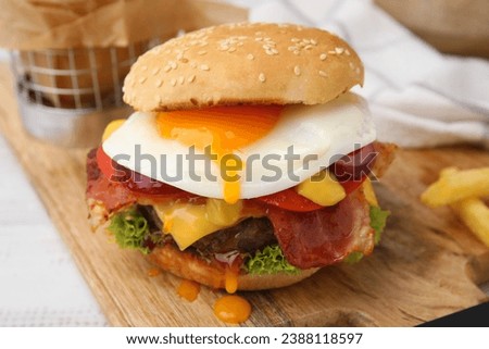 Delicious burger with fried egg on white wooden table, closeup