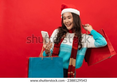Young asian woman wears green clothes Santa hat hold open shopping package bags isolated on  red background.

