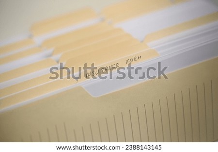 A stack of papers in filing cabinet with inscription insurance form background