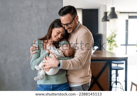 Peaceful young married couple enjoying being family, parents, holding new born baby in arms Royalty-Free Stock Photo #2388145113