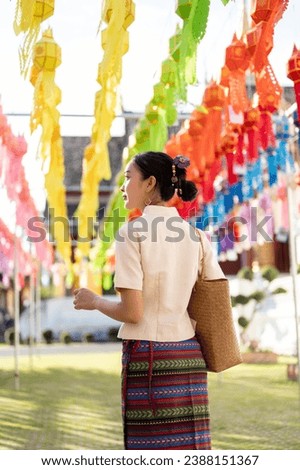 A beautiful and happy young Asian-Thai woman in a traditional Thai-Lanna dress is enjoying in a Thai-Lanna lantern festival or Yi Peng at a temple in Chiang mai. Lanna Loy Krathong festival Royalty-Free Stock Photo #2388151367