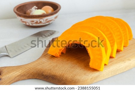 Half of a Hokkaido pumpkin, peeled and sliced, lies on a cutting board. The process of cooking autumn cream soup. Concept of healthy food. Vegan and vegetarian dishes. Horizontal orientation.