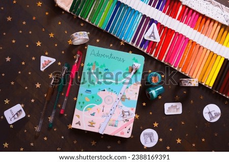 
Art desk for creative activities in a notebook. Art materials for bullet journal practice. Colored pencils, stickers, stamps. Artist's life. Paper lover