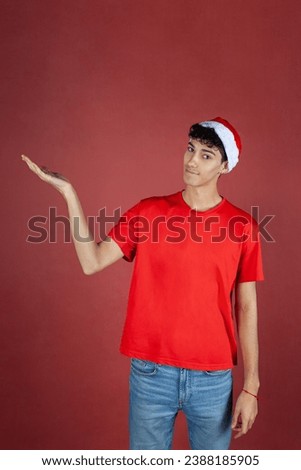 Boy with Santa Hat and Red T-shirt Pointing on Red Background