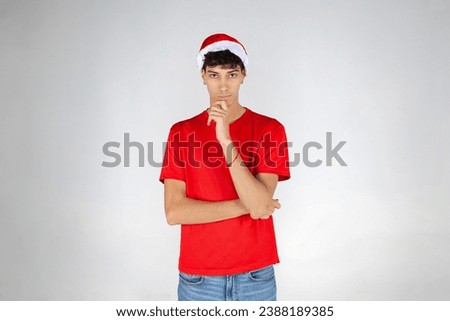 Young Boy with Santa Hat and Red T-shirt, Thinking on White Background. Christmas.